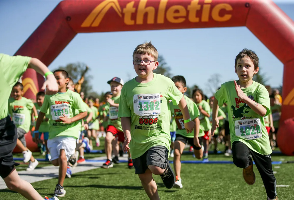 large group of kids running a race wearing green tshirts