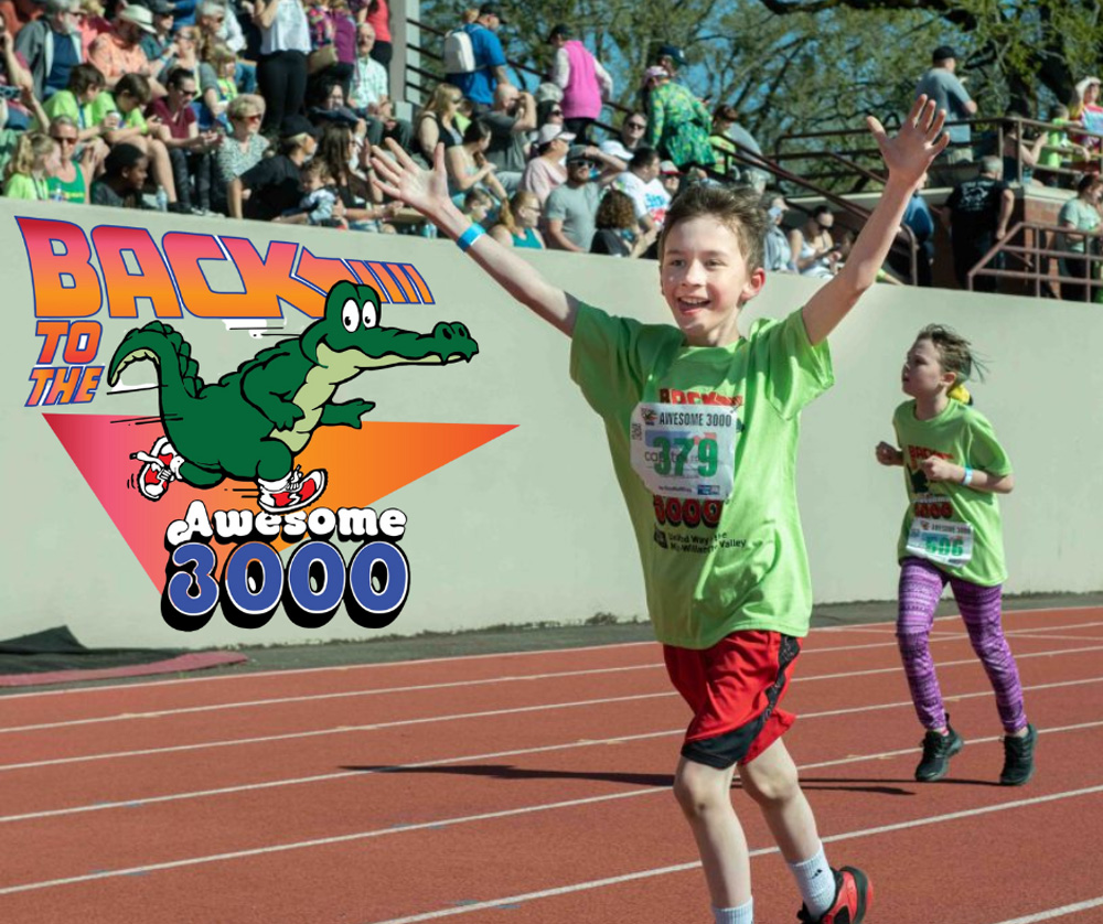child in front running a race on a track smiling with his arms in the air and a young girl running behind him