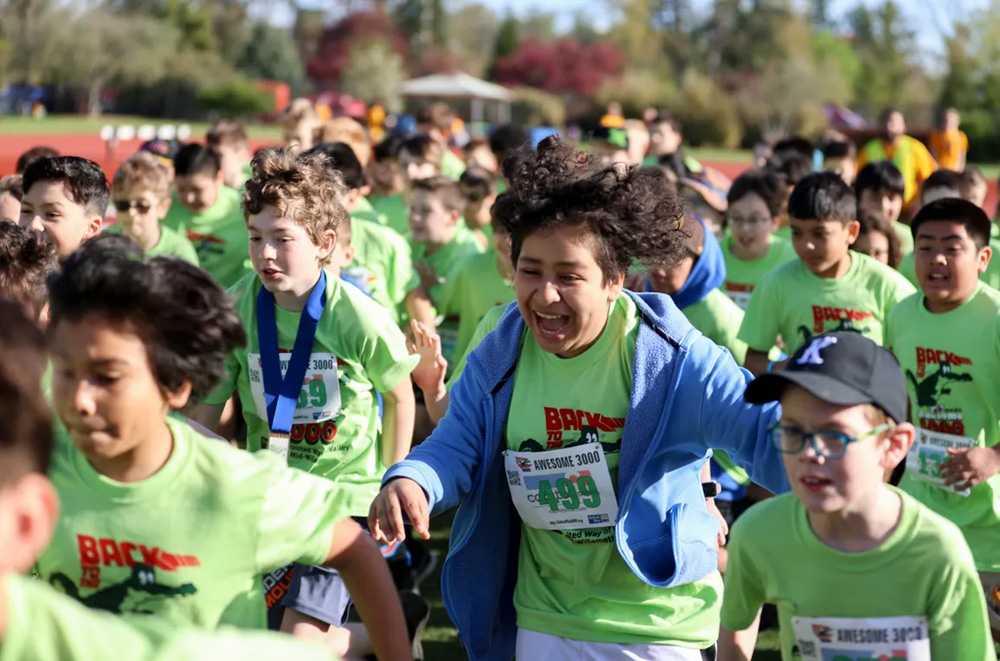 kids running, laughing and smiling in a race wearing green t-shirts